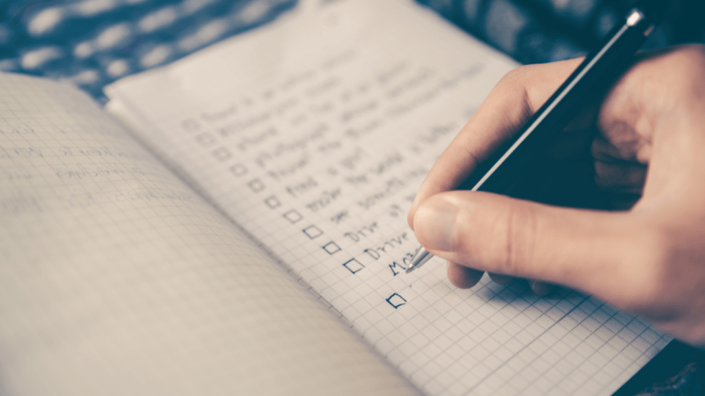 A person's hands writing in a notebook