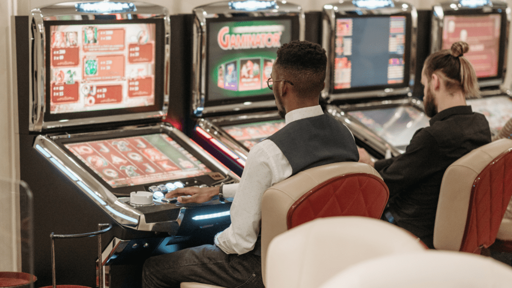 two people sitting in front of slot machines in a casino