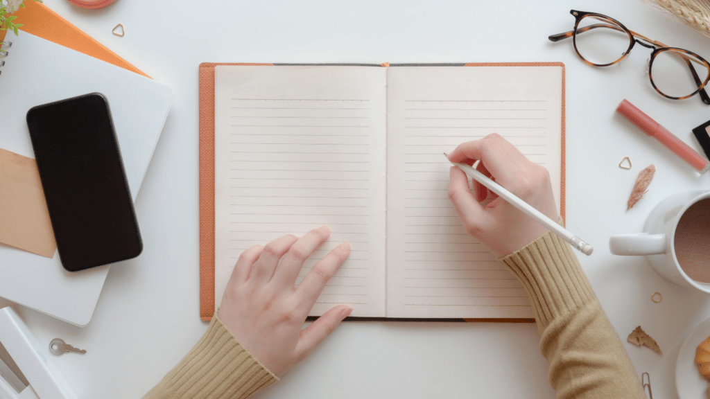 A person's hands writing in a notebook