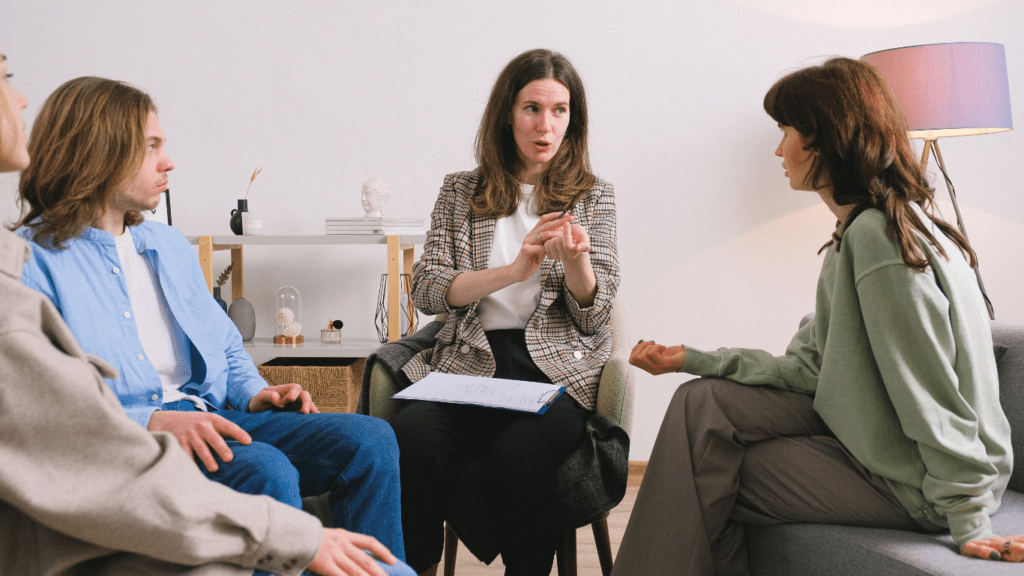 a group of people sitting on a couch talking to each other