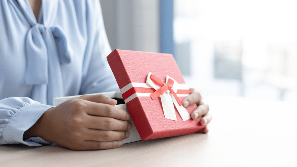 A person holding a gift box on a table