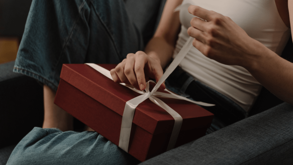 a person sitting on a couch holding a red gift box