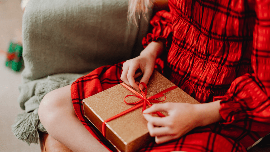 a person sitting on a couch holding a red gift box