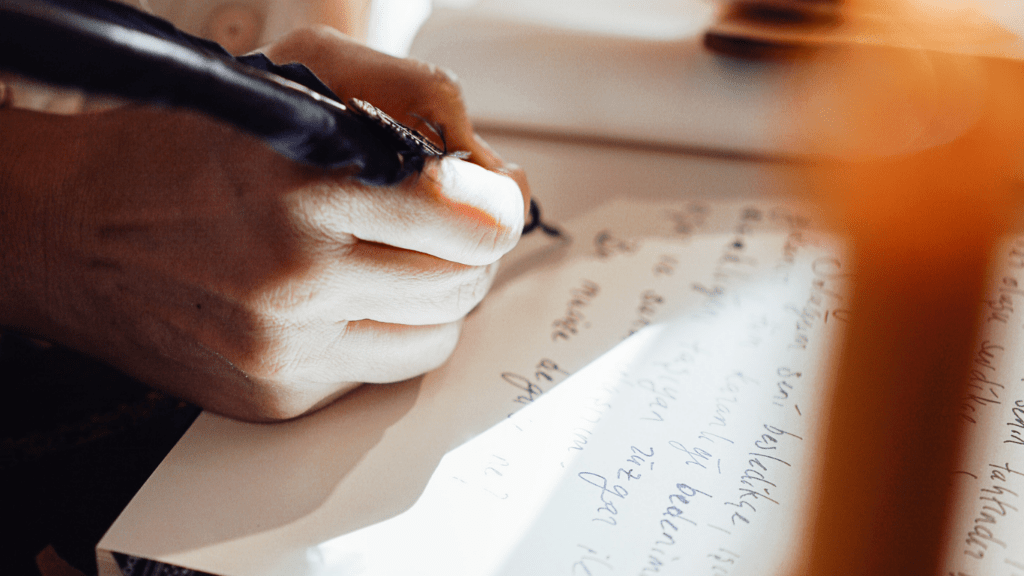 a person writing on a piece of paper with a pen